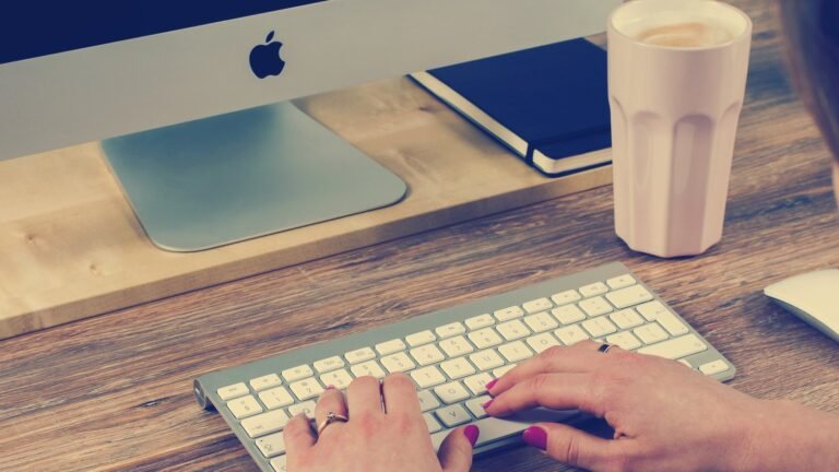 Hands typing on a keyboard at a desk with coffee
