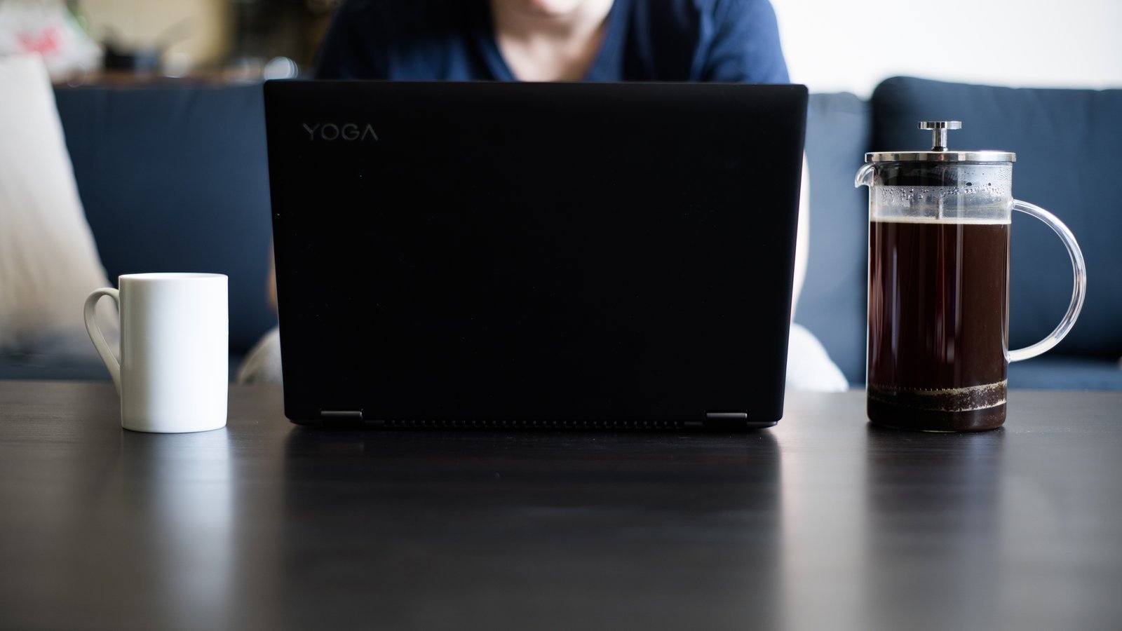 Person working from home on a laptop with coffee, writing content