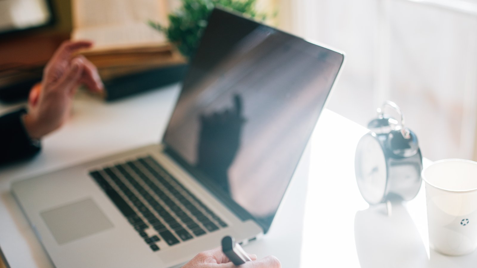 Person writing notes while working on a laptop