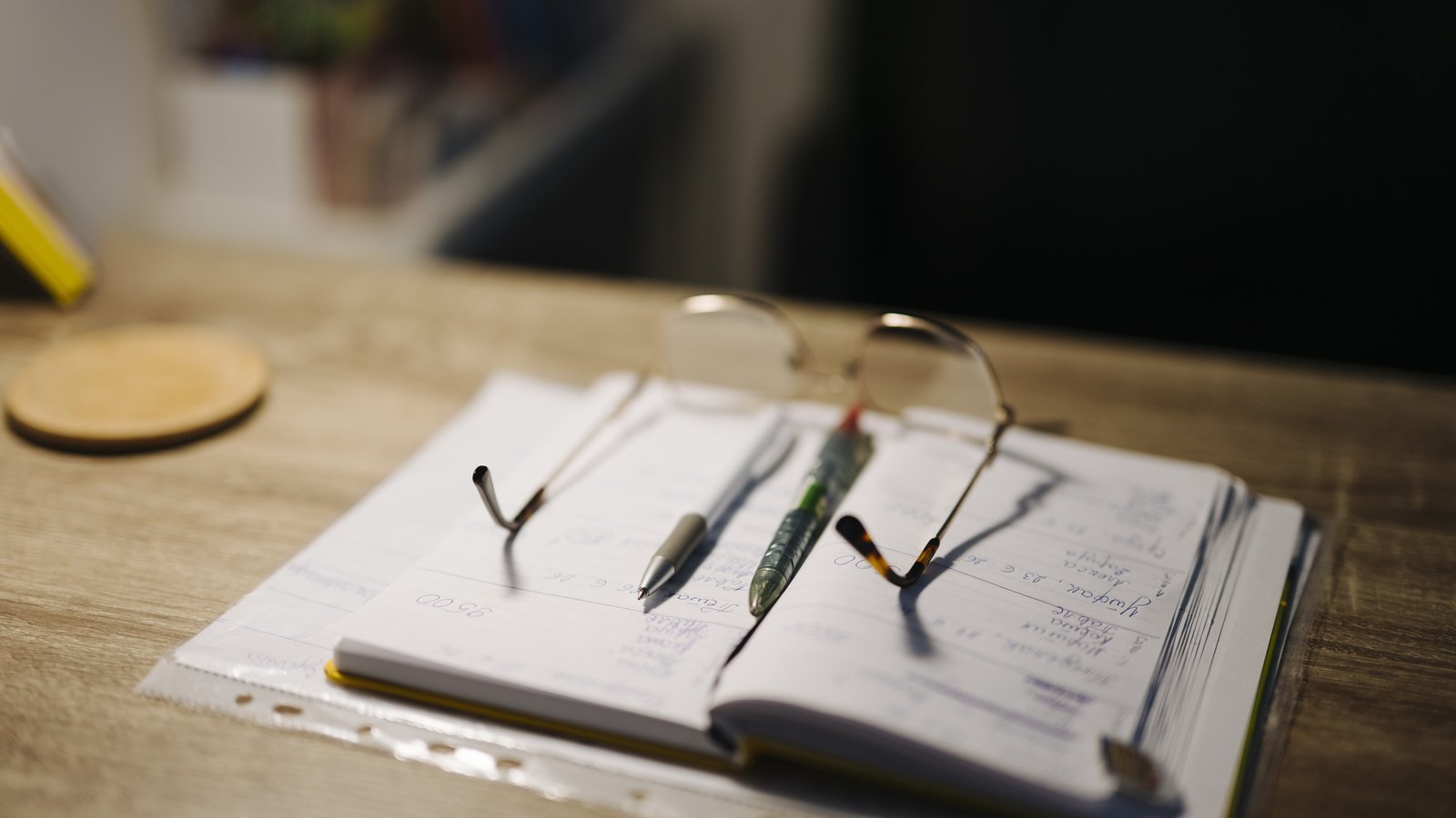 Desk with notebook, pens, and glasses for studying