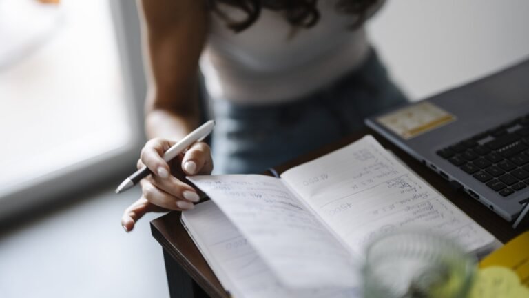 Person writing notes by hand in a notebook at a desk