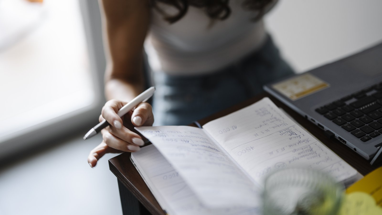 Person writing notes by hand in a notebook at a desk